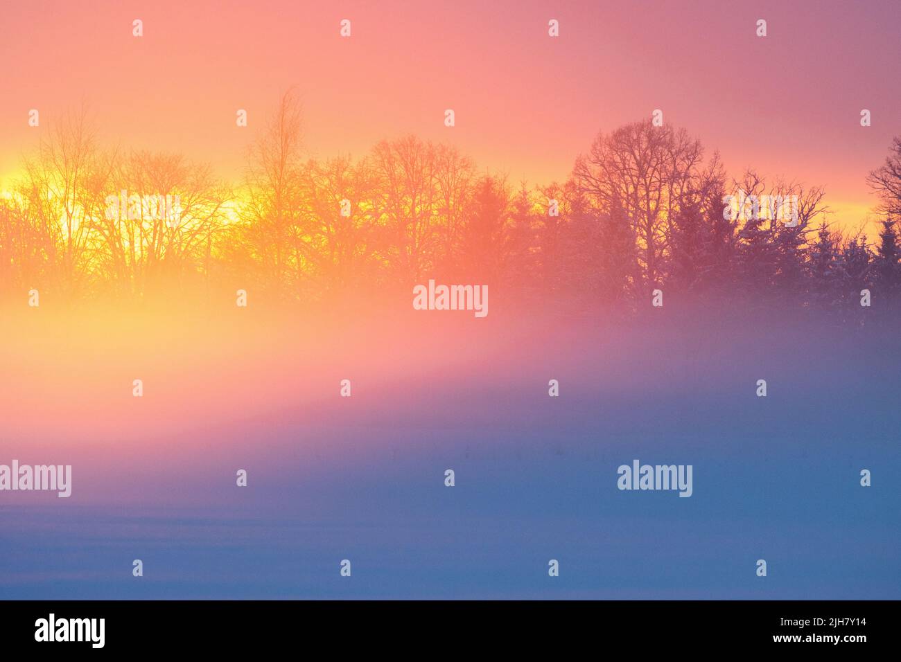 A wintry sunset with vibrant light reflecting on rising mist Stock Photo