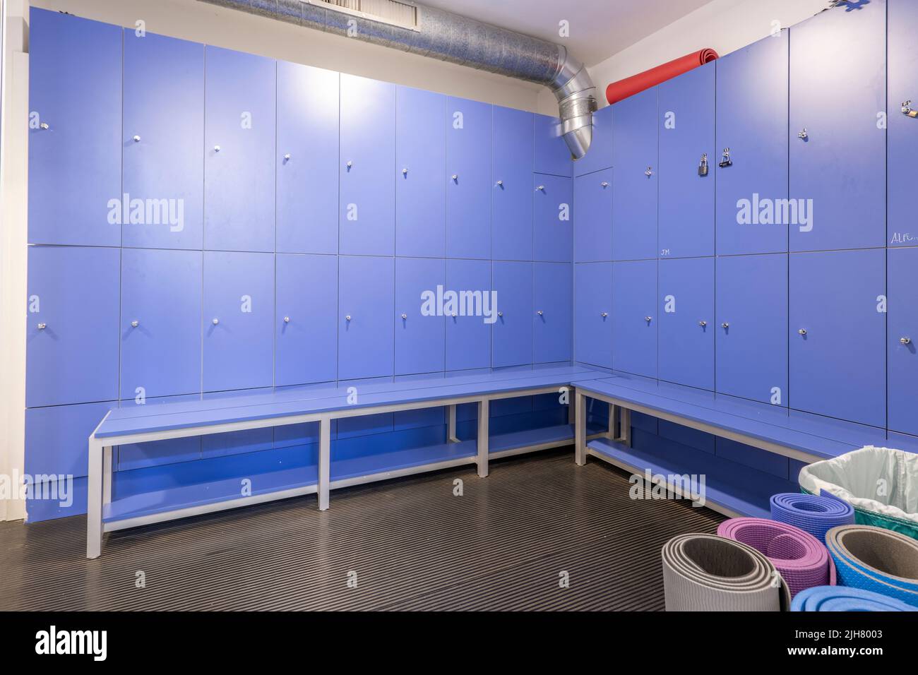 Blue wooden lockers with matching bench seats in a gym locker room Stock Photo