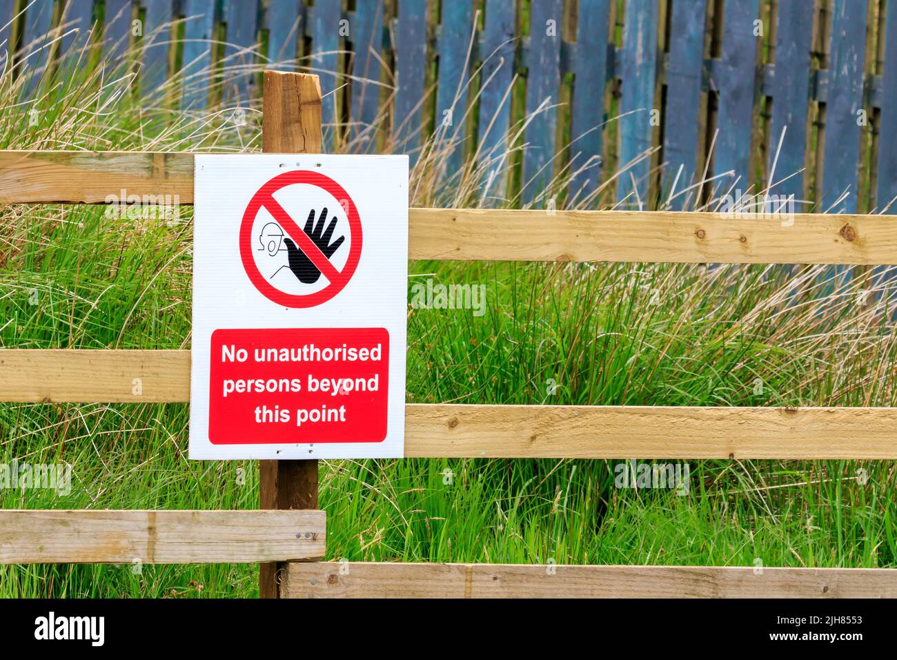 No unauthorised persons beyond this point sign fitted to a wooden fence Stock Photo
