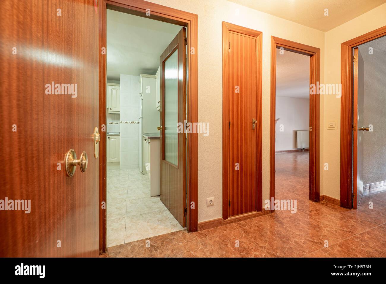 Hallway of a house with wooden doors, fitted wardrobes, reddish ges