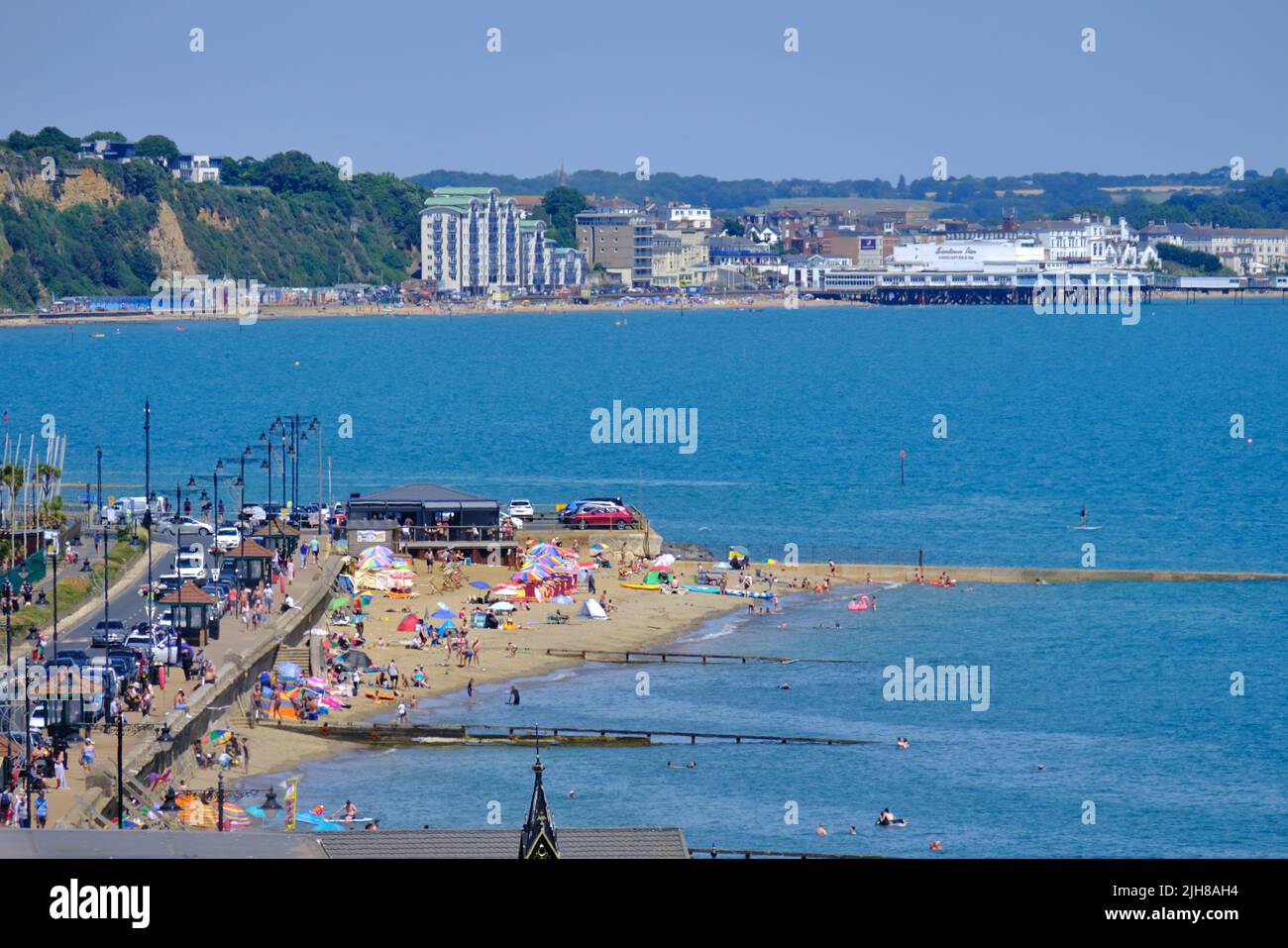 Shanklin, UK, 16th July, 2022. The view across Shanklin (foreground) and Sandown in the distance on the east coast of the Isle of Wight. Visitors make the most of the continuing hot, dry and sunny weather, with temperatures expected to peak on Monday and Tuesday of next week. Parts of England have been issued a Red Extreme weather warning by the Met Office as the mercury has been given a 50% chance of hitting 40 degrees celcius. Credit: Eleventh Hour Photography/Alamy Live News Stock Photo