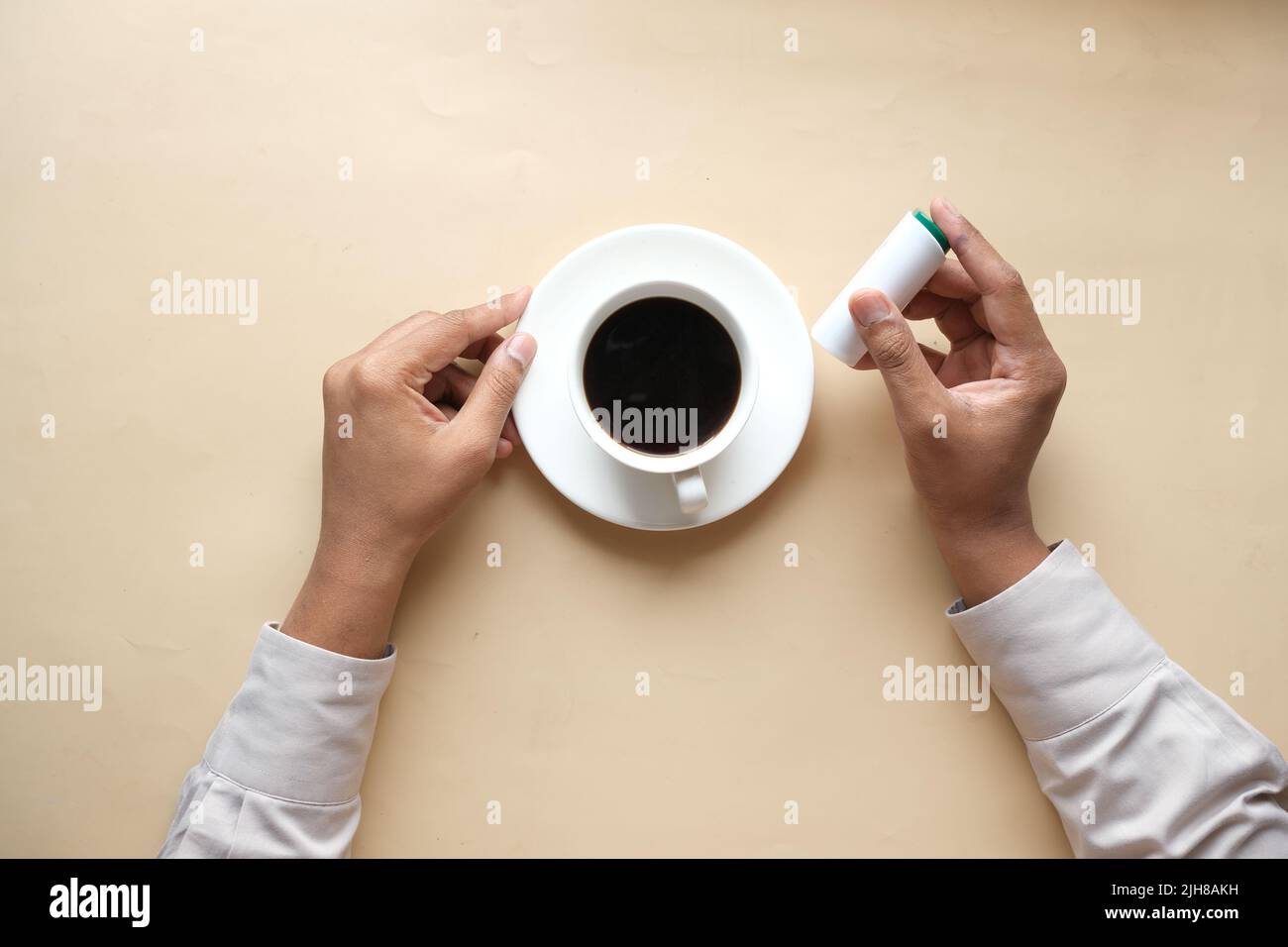 young man putting artificial sweetener in tea, Stock Photo
