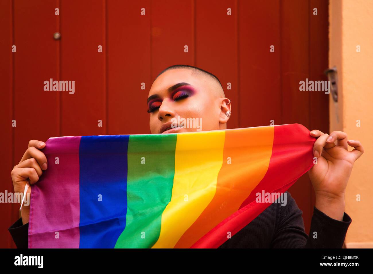 A Hispanic nonbinary person holding a pride flag Stock Photo Alamy