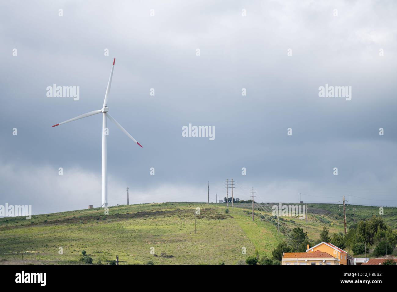 A beautiful view of a wind turbine on a hill under the cloudy sky Stock ...