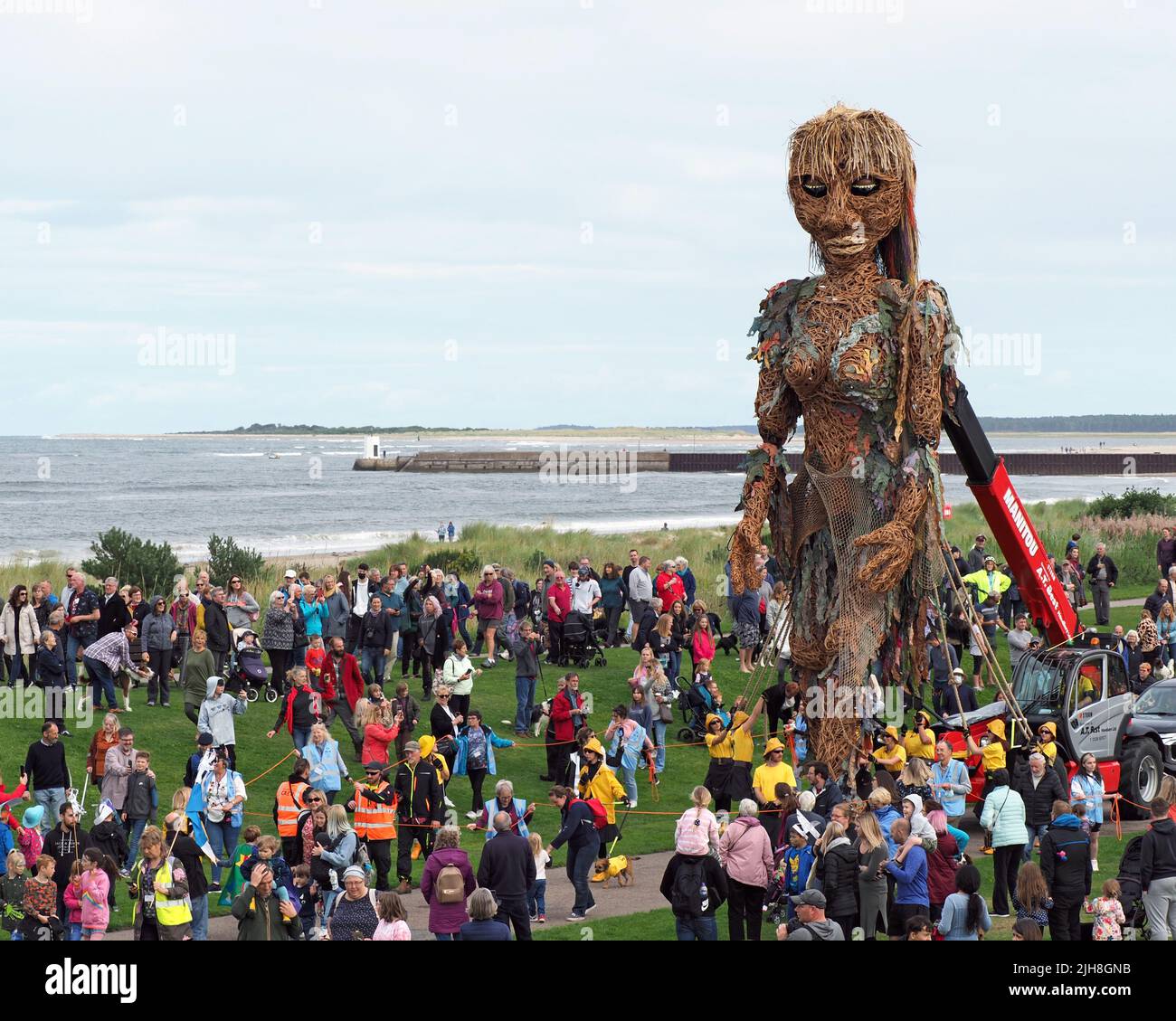 Storm, the mythical sea goddess walking amongst people at Nairn Links on an overcast day. She is a 10 metre tall puppet. Stock Photo