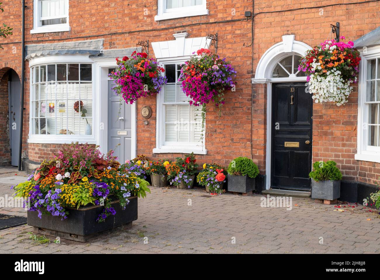 Hanging baskets of flowers on house fronts in the town of Pershore, Worcestershire, UK Stock Photo