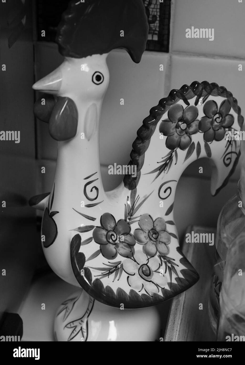 A vertical grayscale of a rooster figurine with floral print in the kitchen Stock Photo