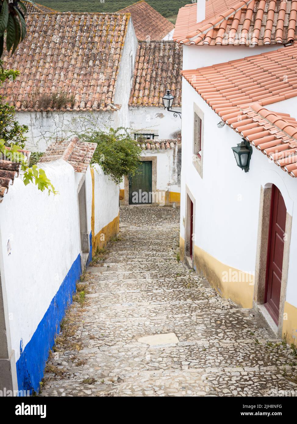 The city of Óbidos, Portugal: Steep alley between old white houses. Stock Photo