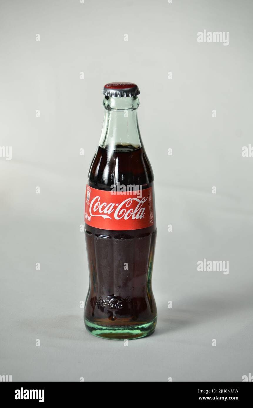 A vertical shot of a bottle of Coca-Cola in a studio in a white wall background Stock Photo