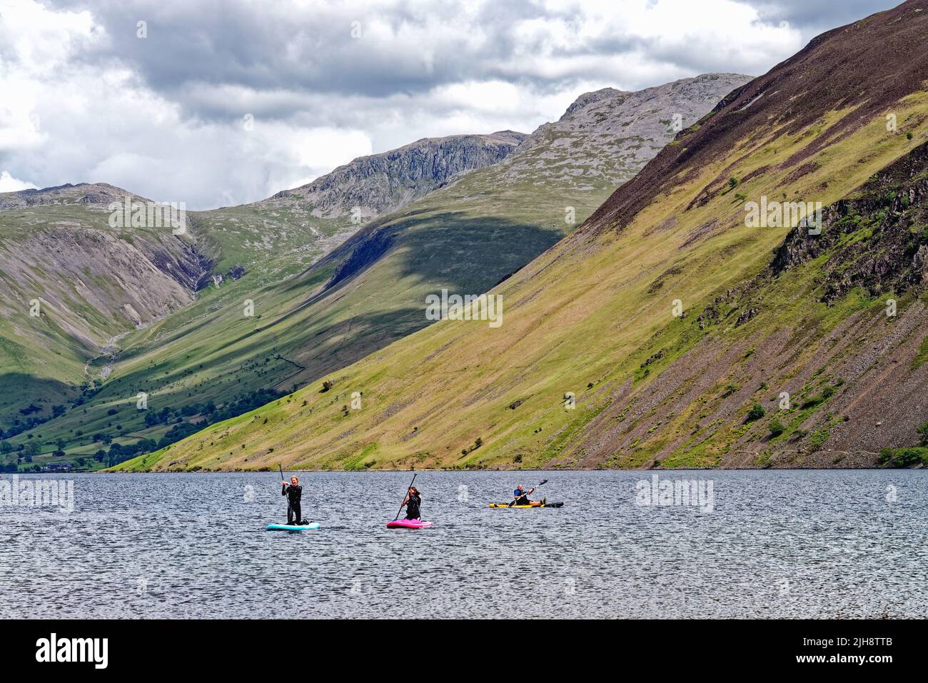 Paddleboarders on Wastwater lake with the dramatic scree slopes in the background, on a summers day Wasdale, Cumbria England UK Stock Photo