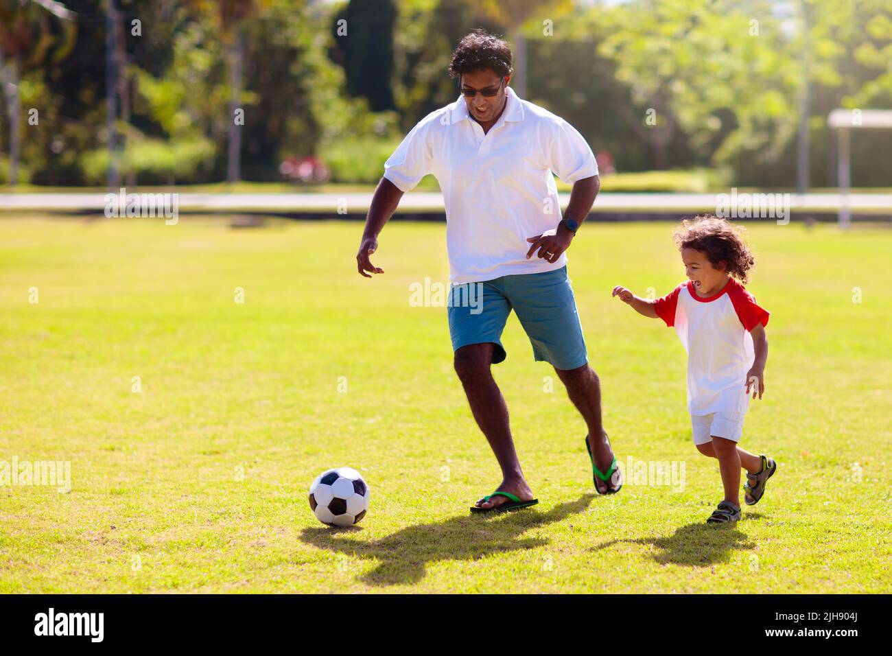 Father and son play football. Dad and little boy play soccer. Young