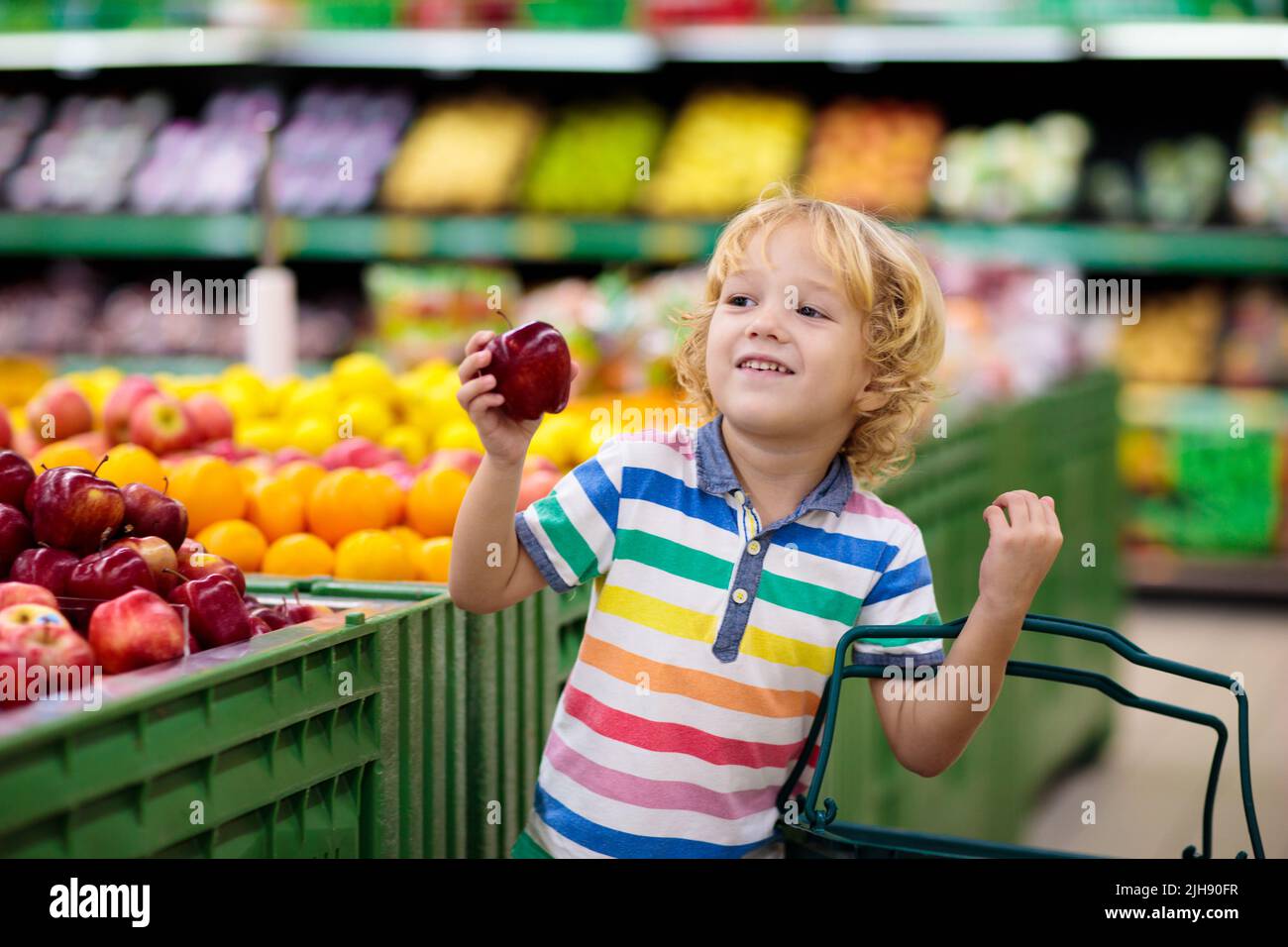 Child in supermarket buying fruit and juice. Kid grocery shopping
