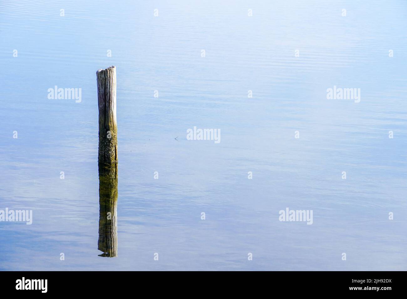 A beautiful shot of a calm seascape with a broken pillar sticking out of the water on the horizon background. Stock Photo