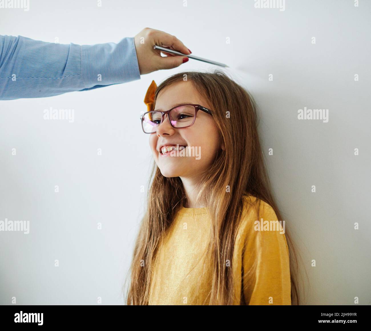daughter mother measuring height growth childhood tall child heigth kid wall cute Stock Photo