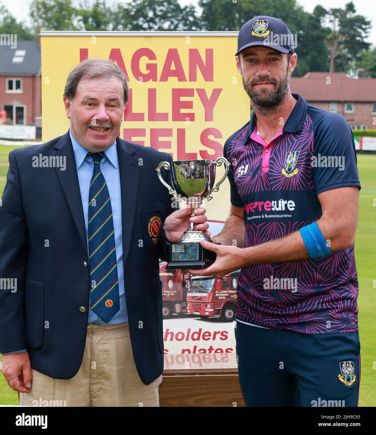 The Lawn, Waringstown, Northern Ireland, UK. 16 Jul 2022. The Lagan Valley Steels Twenty 20 Cup Final 2022. CIYMS v CSNI – CIYMS won by 16 runs (DLS) in a rain-affected match. Northern Cricket Union President Roger Bell presents the cup to CIYMS captain Nigel Jones. Credit: David Hunter/Alamy Live News Stock Photo