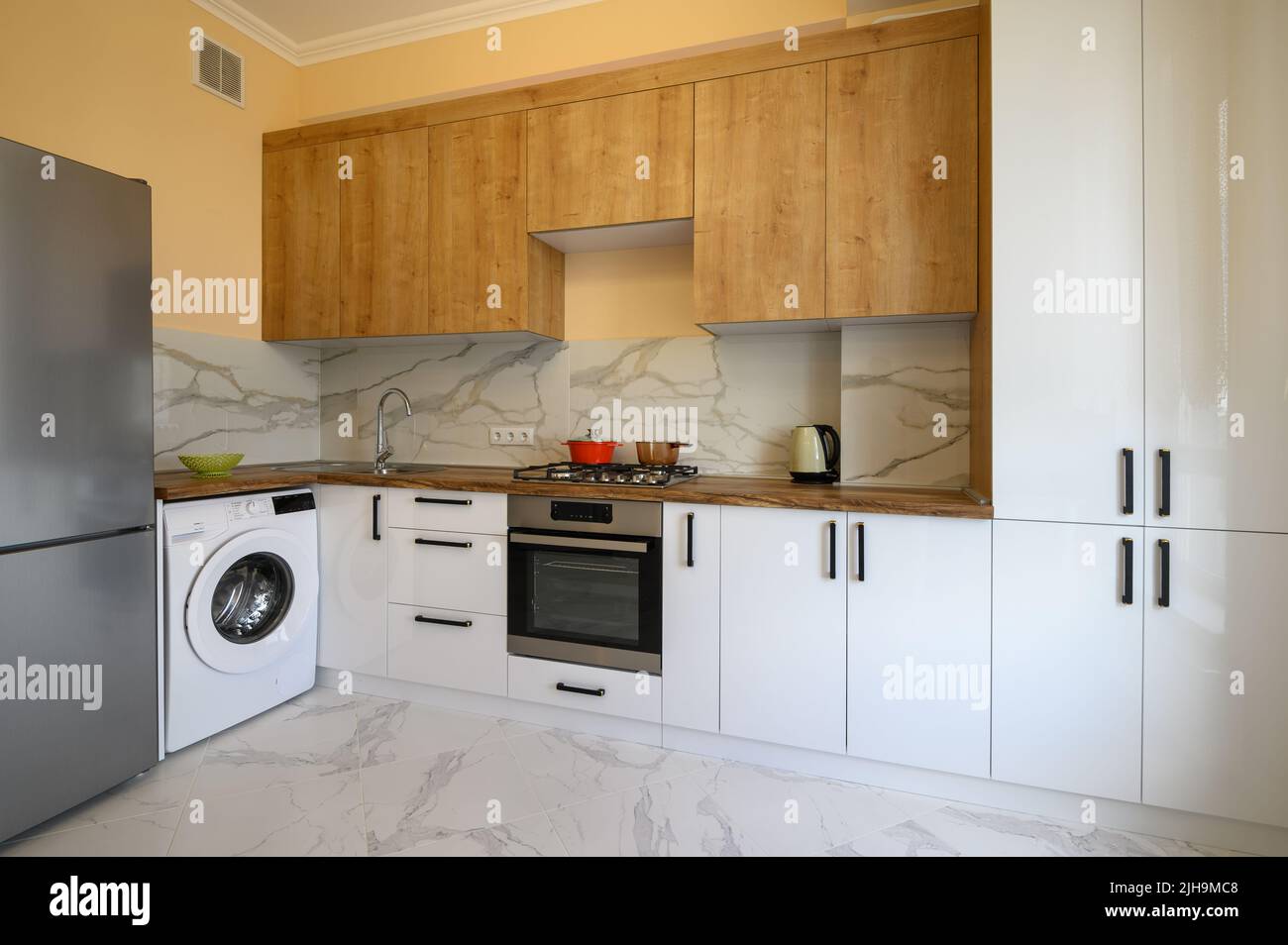 White and yellow wooden modern kitchen interior Stock Photo - Alamy