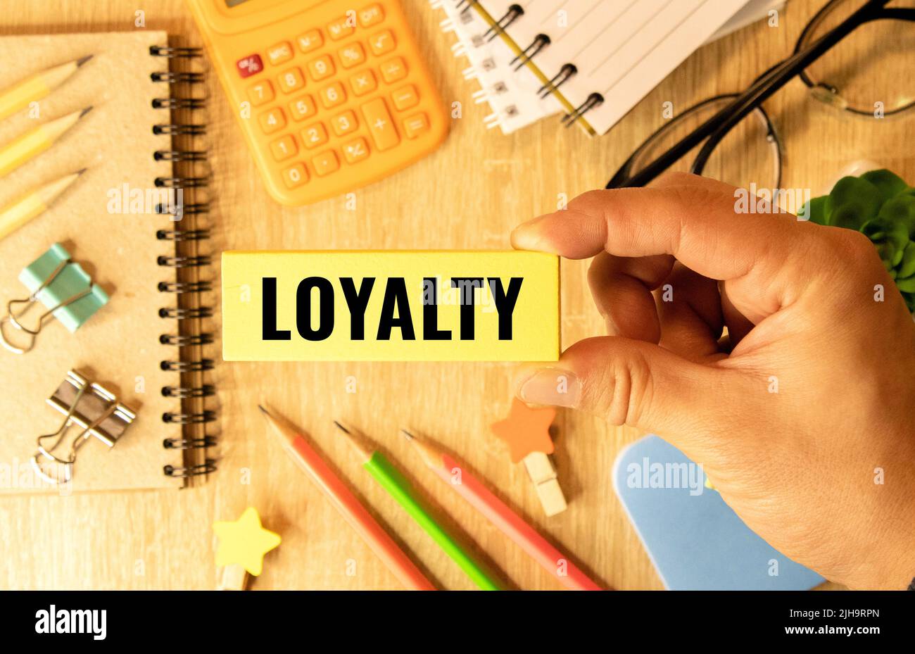 LOYALTY wood word on compressed board with human's finger at Y letter Stock Photo