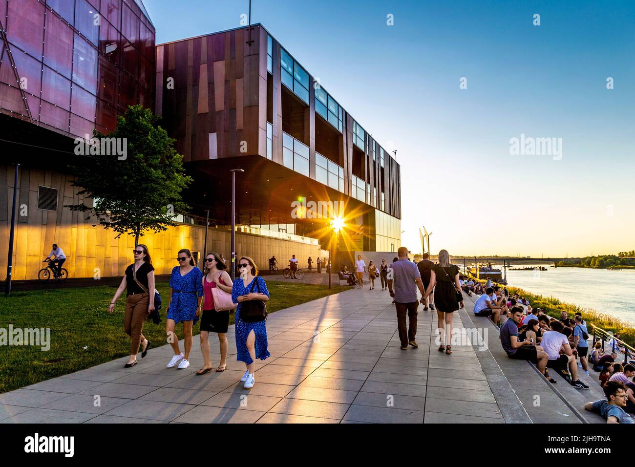 Copernicus Science Centre (Centrum Nauki Kopernik) and people walking along Vistula River at sunset in Powiśle, Warsaw, Poland Stock Photo
