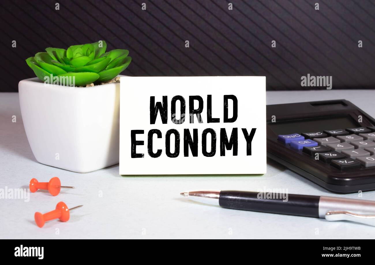 black pen and a notebook with the text WORLD ECONOMY. Business concept Stock Photo