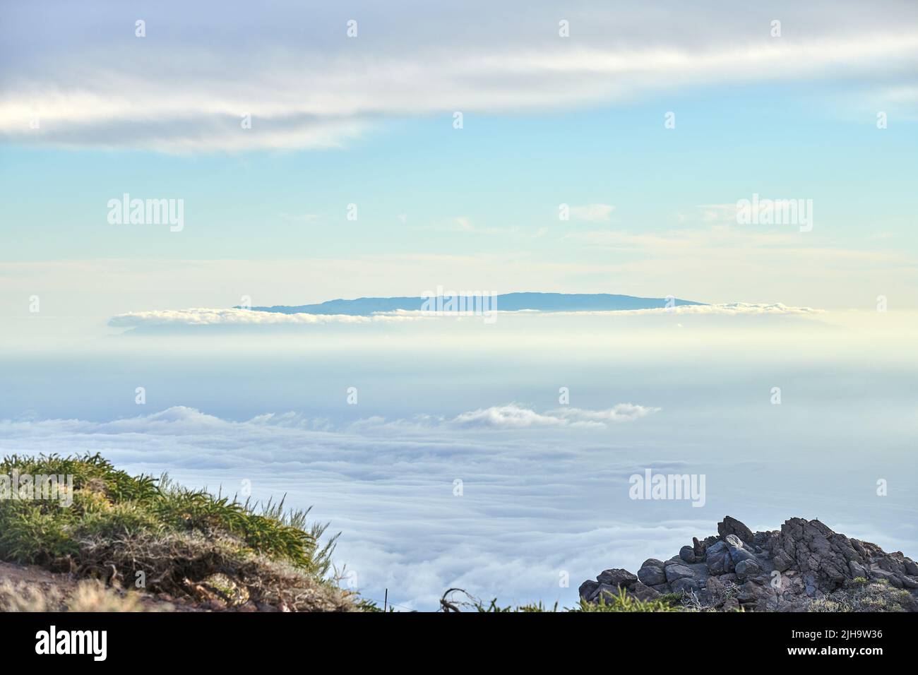 Hiking mountain to view volcano through dense cloud cover in travel or tourism destination. Exploring scenic background skyscape of Roque de Los Stock Photo