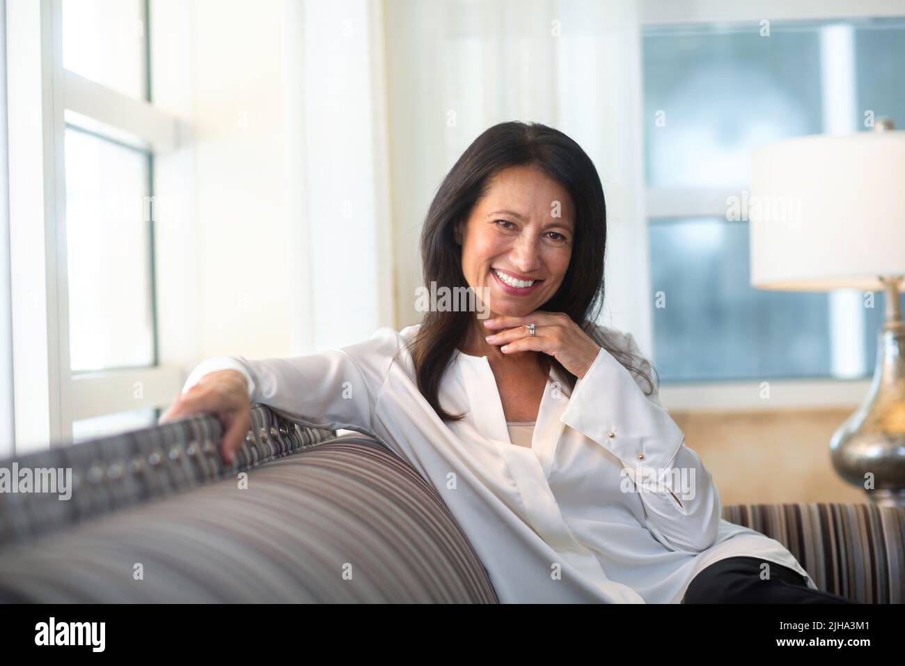 Portrait of a beautiful mature woman sitting on the sofa Stock Photo ...