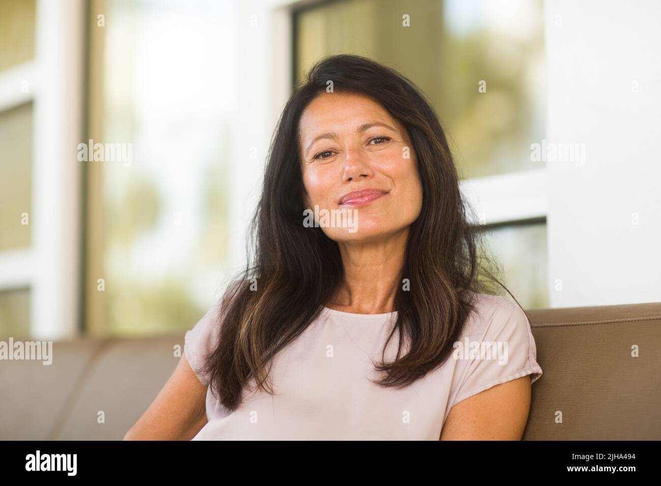 Portrait of a beautiful mature woman sitting on the sofa Stock Photo