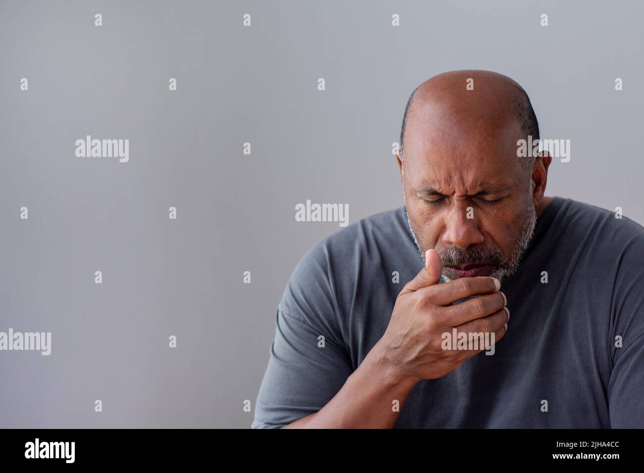 Mature African American man not feeling well who is coughing and has a sore throat. Stock Photo