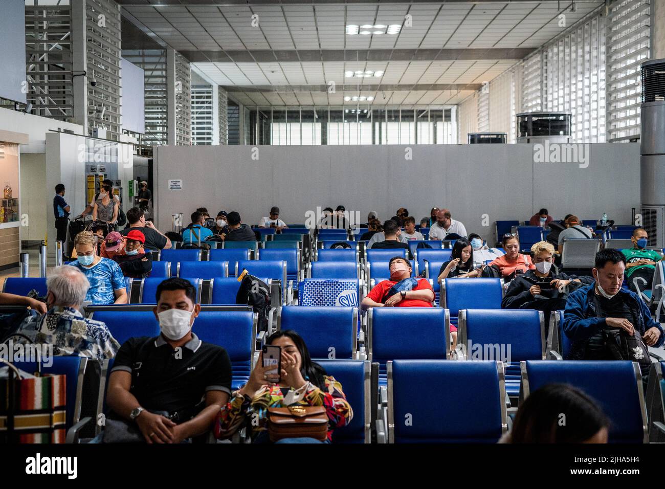 Manila, Philippines. 17 July 2022. A traveler wearing a face mask is seen sleeping at a boarding gate in the international departures terminal at Manila Ninoy Aquino International Airport (MNL). International travel continues amid a worldwide surge in COVID infections from the highly contagious BA.5 variant, leading some countries to roll back pandemic-era travel requirements, including mask mandates and updated vaccine requirements to include booster shots for visa-free entry. Matt Hunt / Neato Credit: Matt Hunt / Neato/Alamy Live News Stock Photo