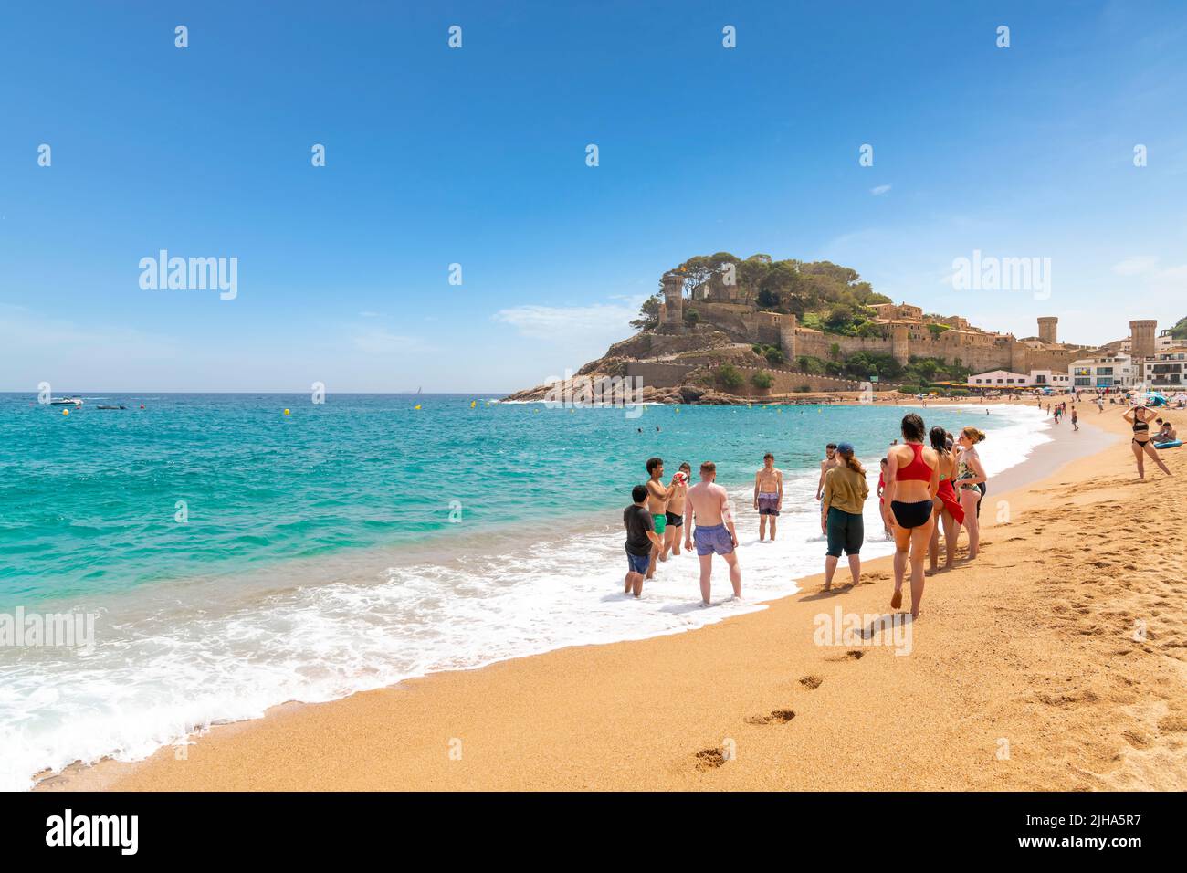Young adults play ball on the sandy Platja Gran beach at the resort town of Tossa de Mar, Spain, on the Costa Brava coast of the Mediterranean Sea. Stock Photo