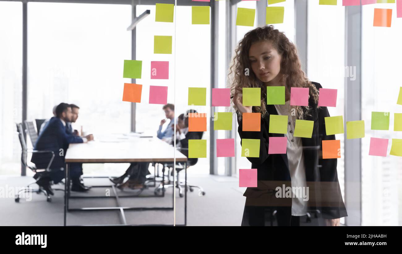 smart businesswoman standing near white flipchart, attaching sticky notes  with copy space Stock Photo by LightFieldStudios