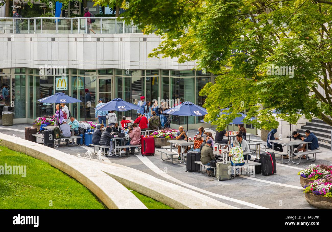 Tourists Having Lunch At Outdoor Restaurant Downtown. Tourists sitting at outdoor cafe tables, with the suitcases Stock Photo