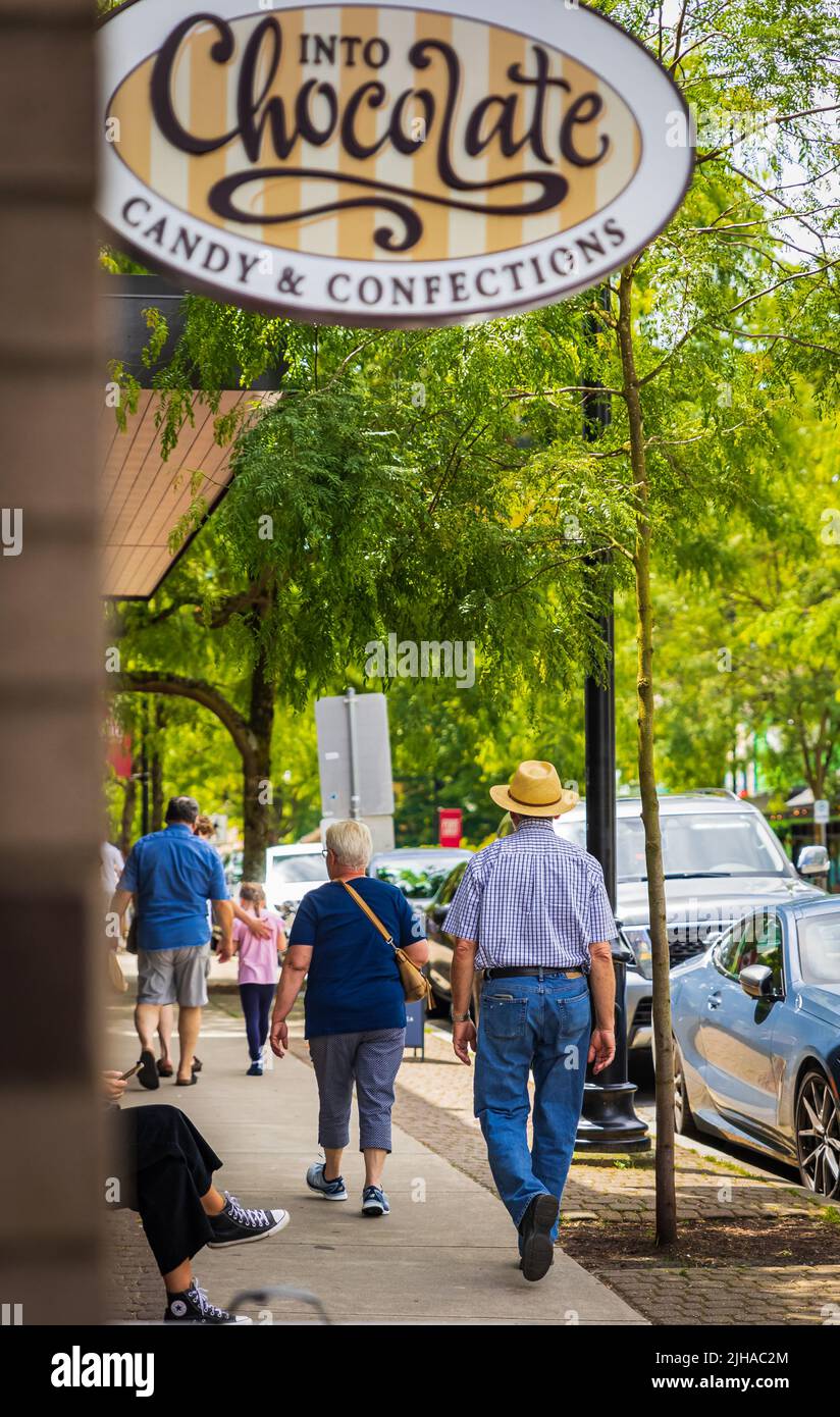 A man in an urban casual lifestyle walking down a sidewalk along street in a city. People on a street Stock Photo