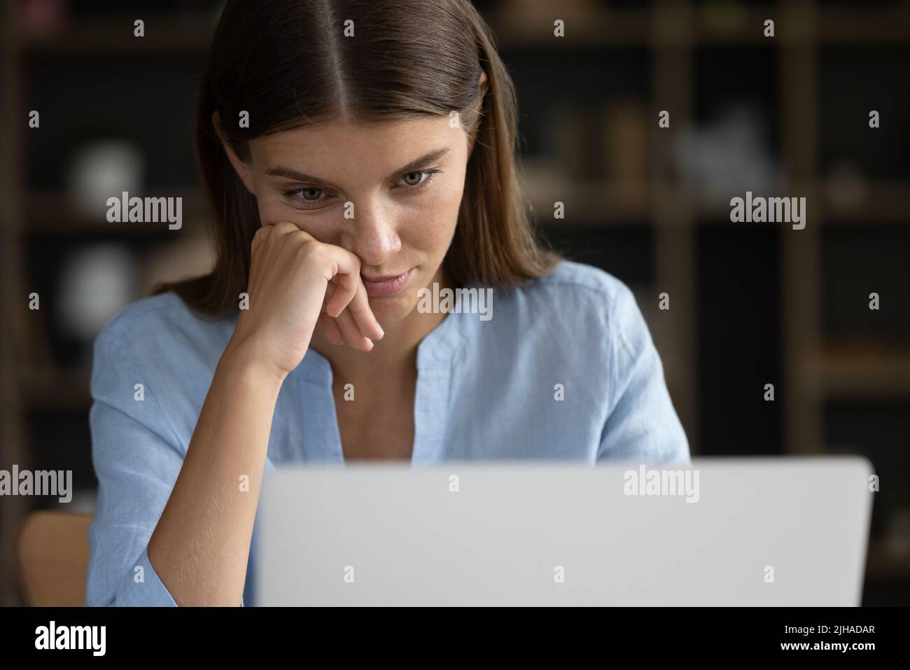Close up face tired unmotivated female, staring at laptop screen Stock Photo