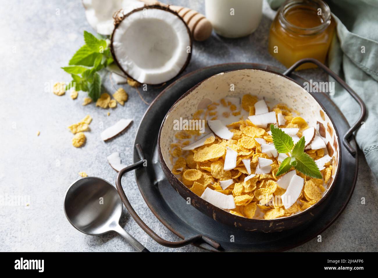 Vegan healthy breakfast. Cereal granola breakfast flakes with coconut non-dairy alternative milk and fresh coconut slices on a stone tabletop. Copy sp Stock Photo