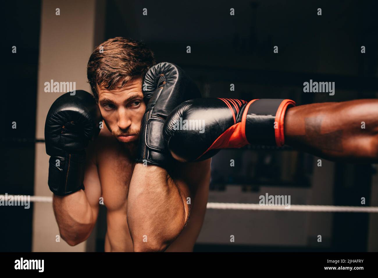 Boxing athlete blocking a punch to his jaw during a match with his