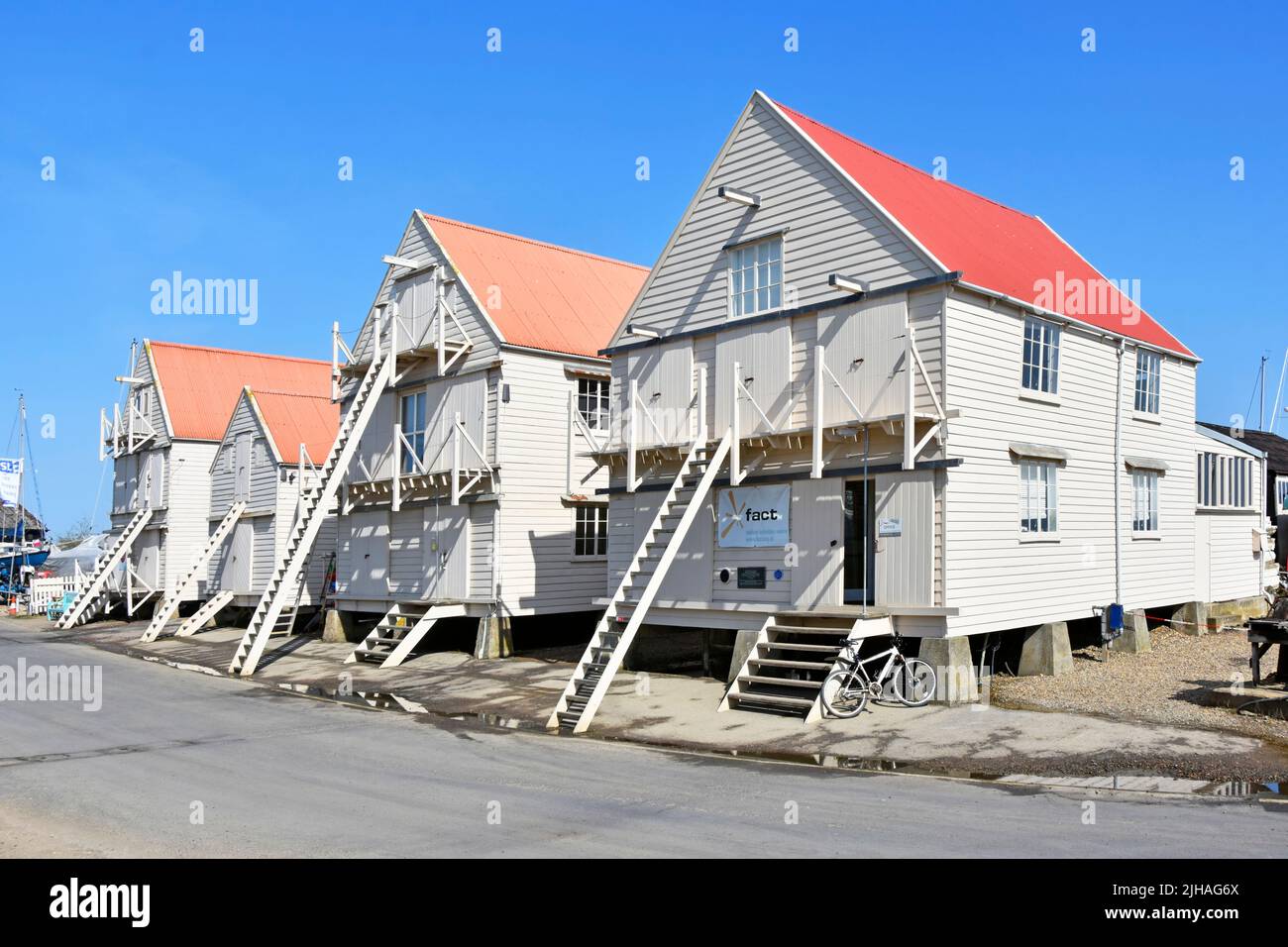 Tollesbury Essex row of weather boarded historical one time sail lofts now for small business use despite steps & ladders required above high tides UK Stock Photo