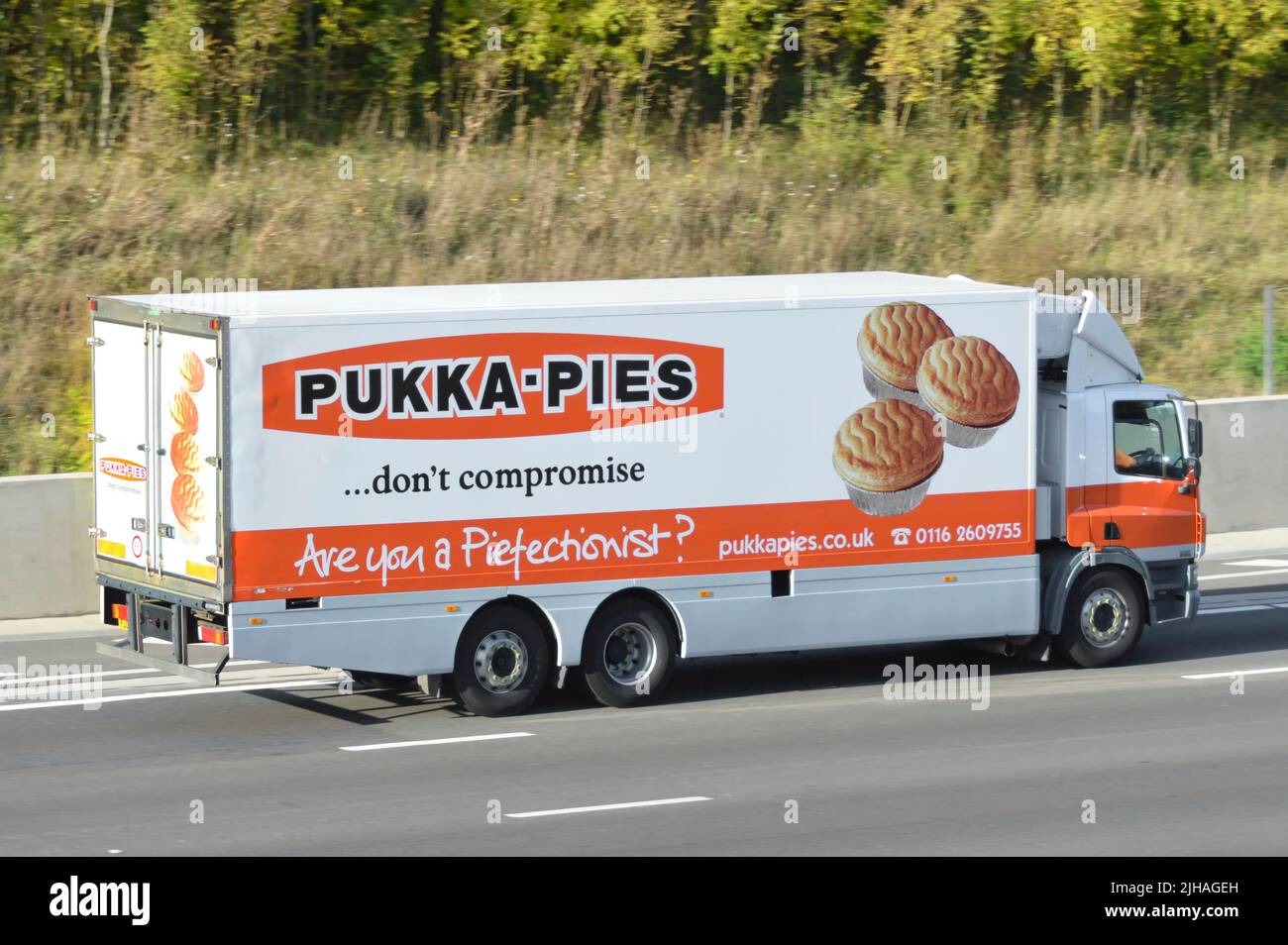 Advertising graphics on side & back view of rigid body hgv chassis cab supply chain lorry truck for Pukka-Pies food brand business driving on UK road Stock Photo