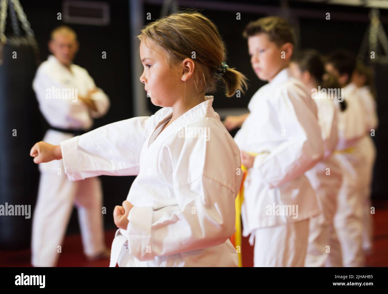 Kids in kimonos practicing karate techniques in group workout at