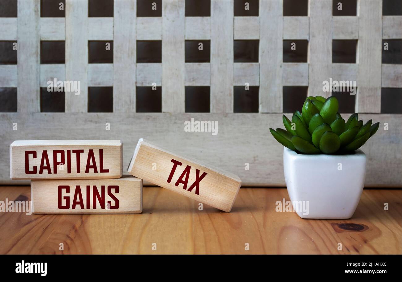 CAPITAL GAINS TAX - words on wooden blocks on a beautiful background. Business and hybrid work culture concept, copy space. Stock Photo