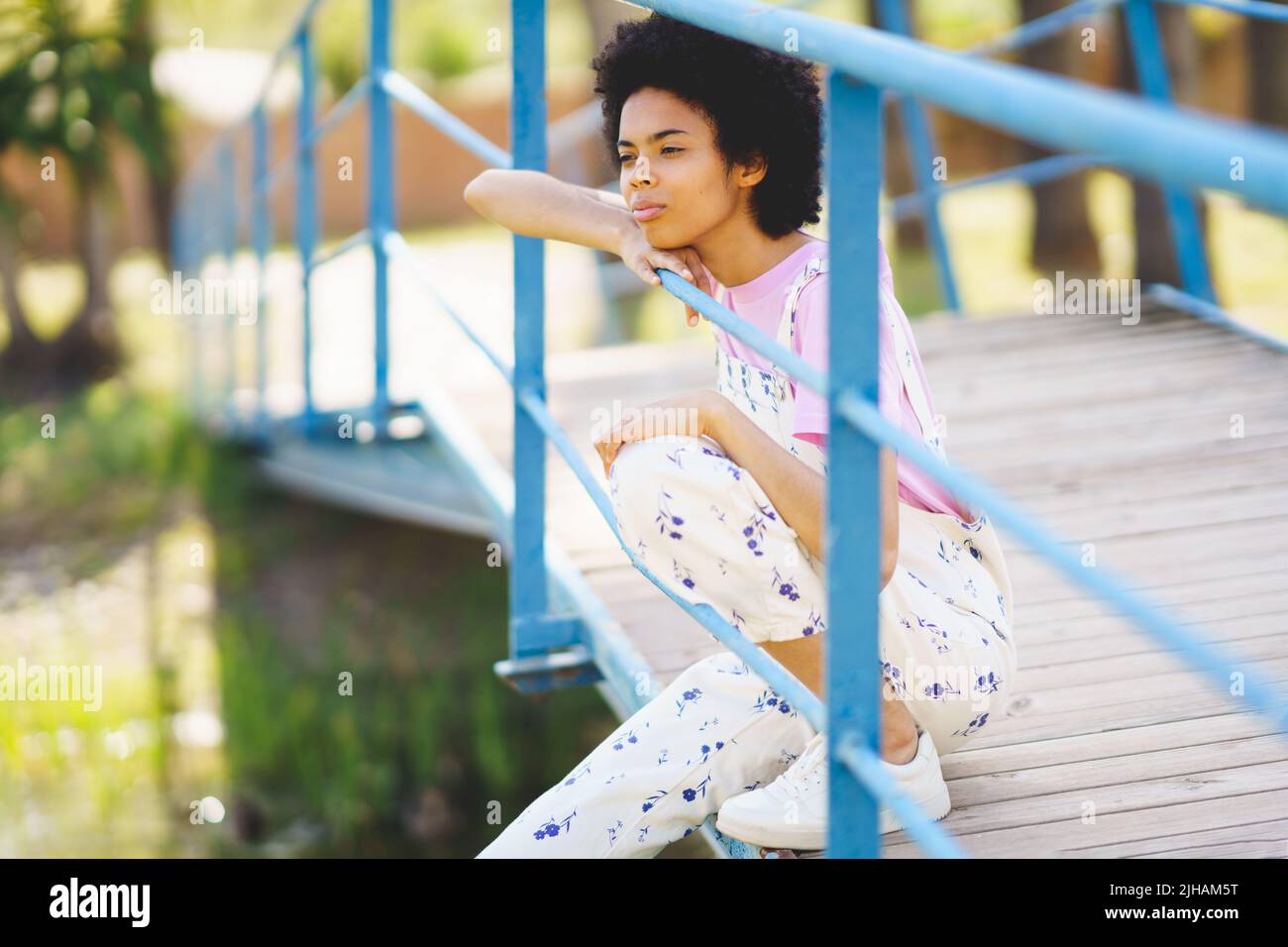 Dreamy black woman sitting on footbridge Stock Photo