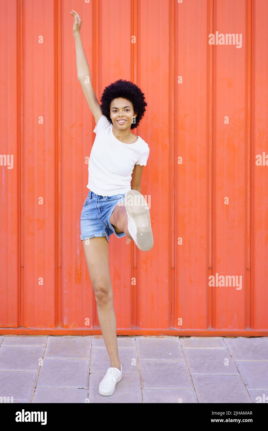 Content black woman raising leg near wall Stock Photo
