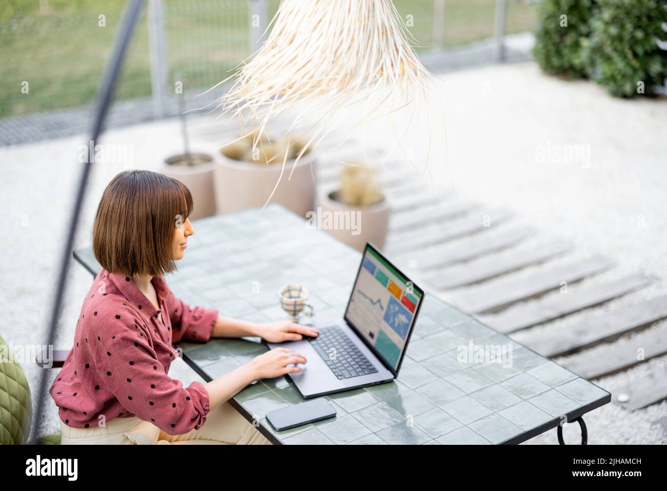 Woman works on laptop while sitting by the table outdoors Stock Photo ...