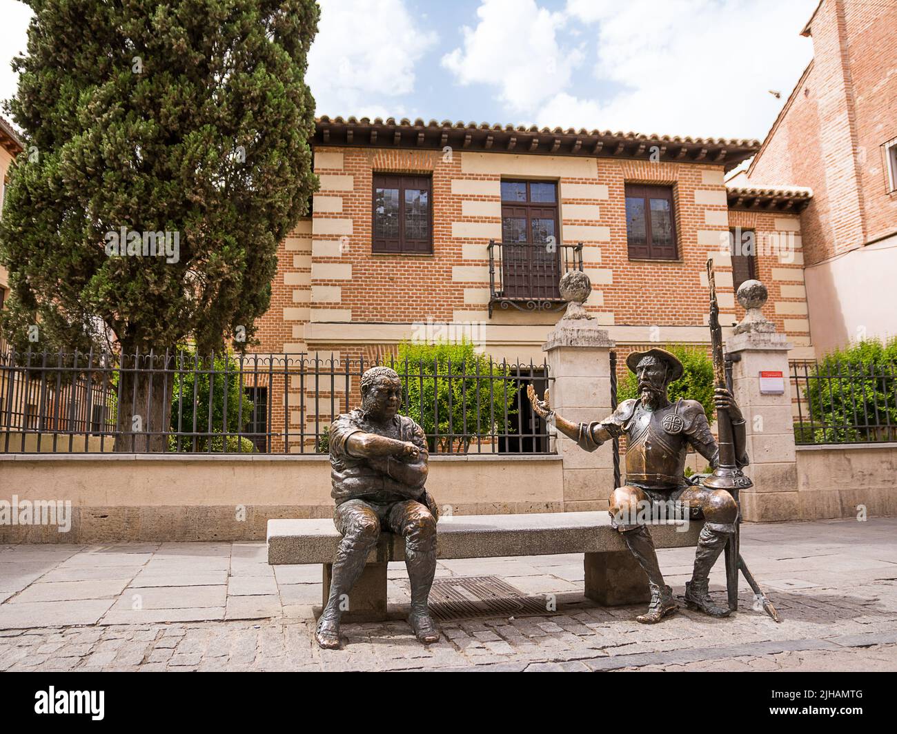 Alcalá de Henares, Spain - June 18, 2022: The statues of Don Quixote and Sancho Panza in the foreground and in the background the house museum birthpl Stock Photo