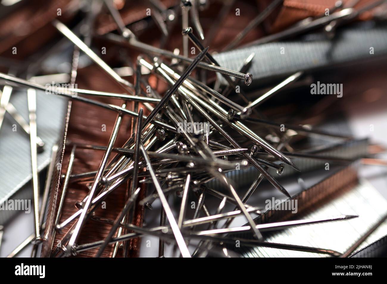 A pile of stapler staples and nickel plated steel pins, stack of paper ...