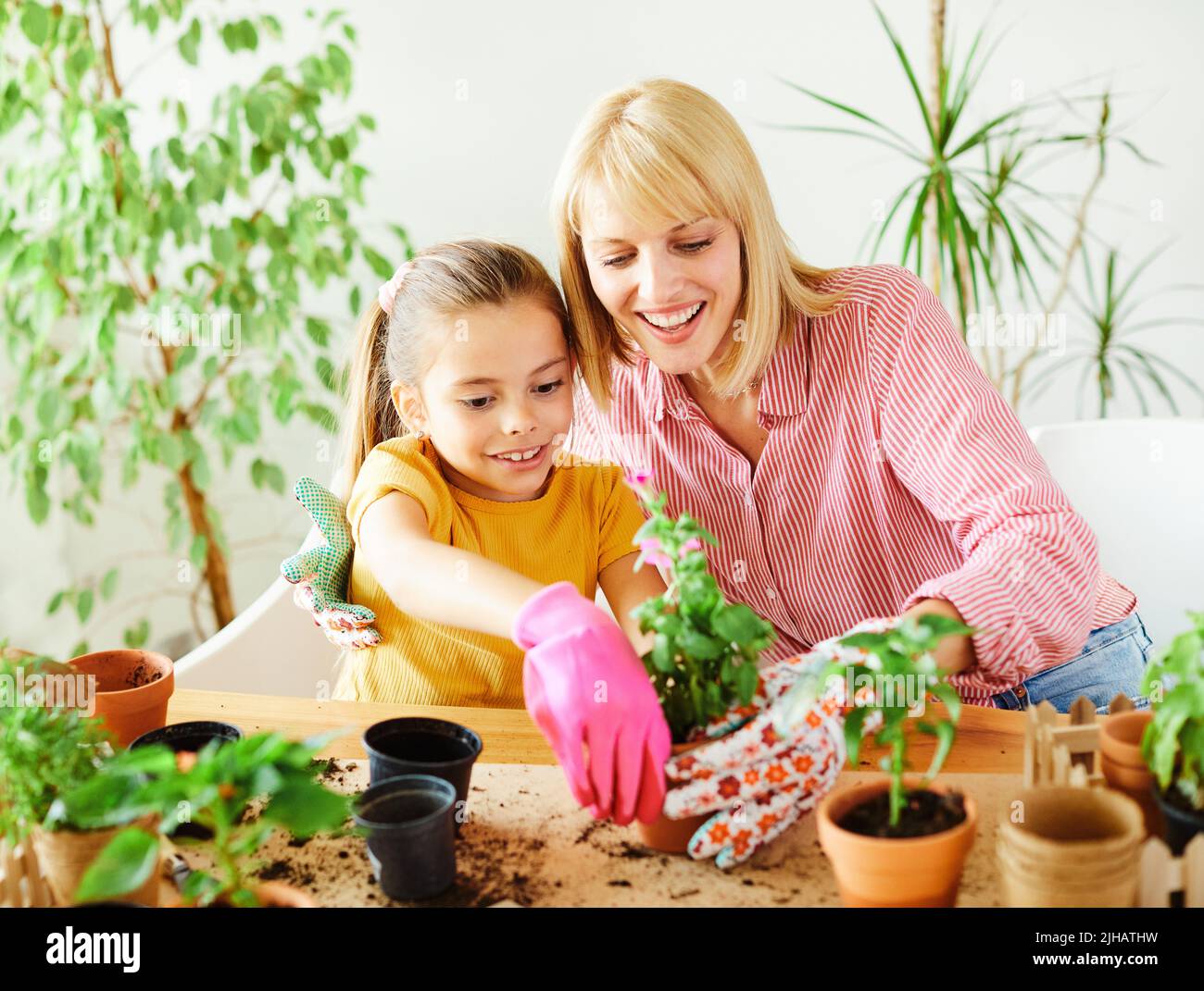 child mother family parent home woman flower gardening plant garden daughter kid together greenhouse Stock Photo