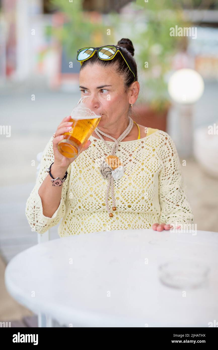 Portrait of woman drinking beer at beach cafe Stock Photo