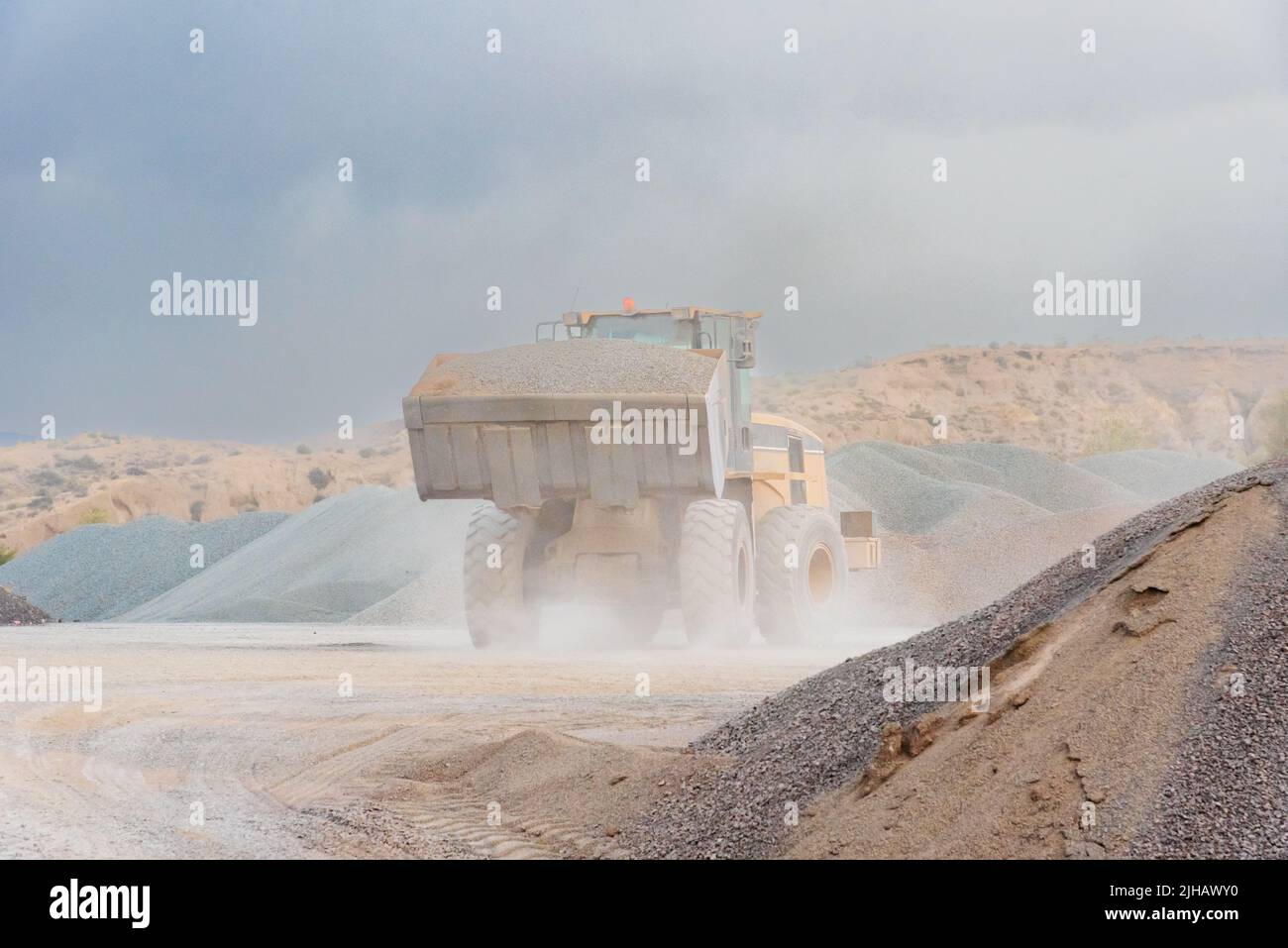 Dust covered excavator shovel loaded with sand in a quarry. Stock Photo