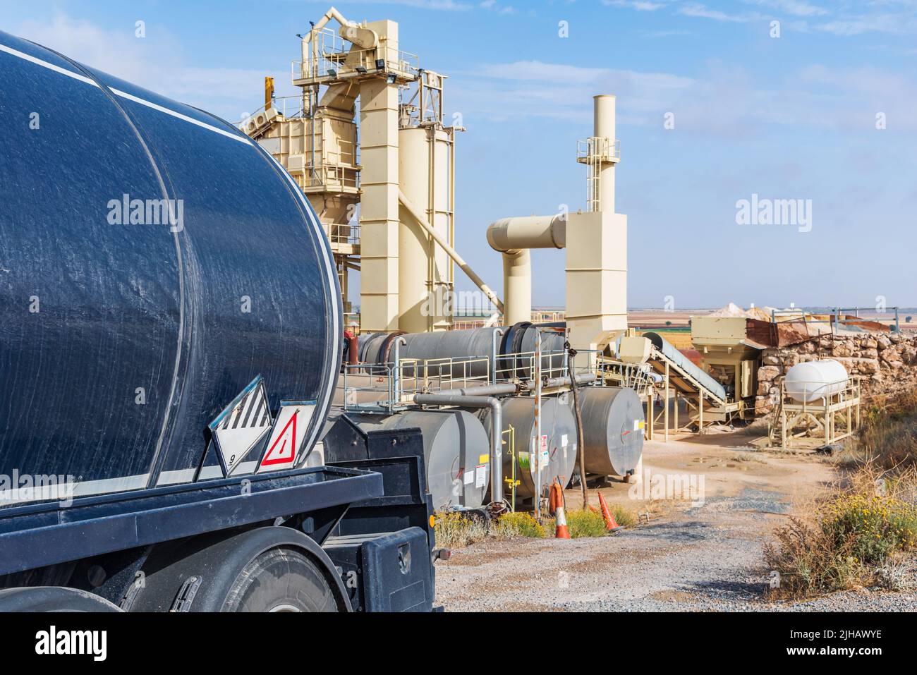 Tanker truck loaded with high temperature bitumen entering an agglomerated asphalt manufacturing plant . Stock Photo