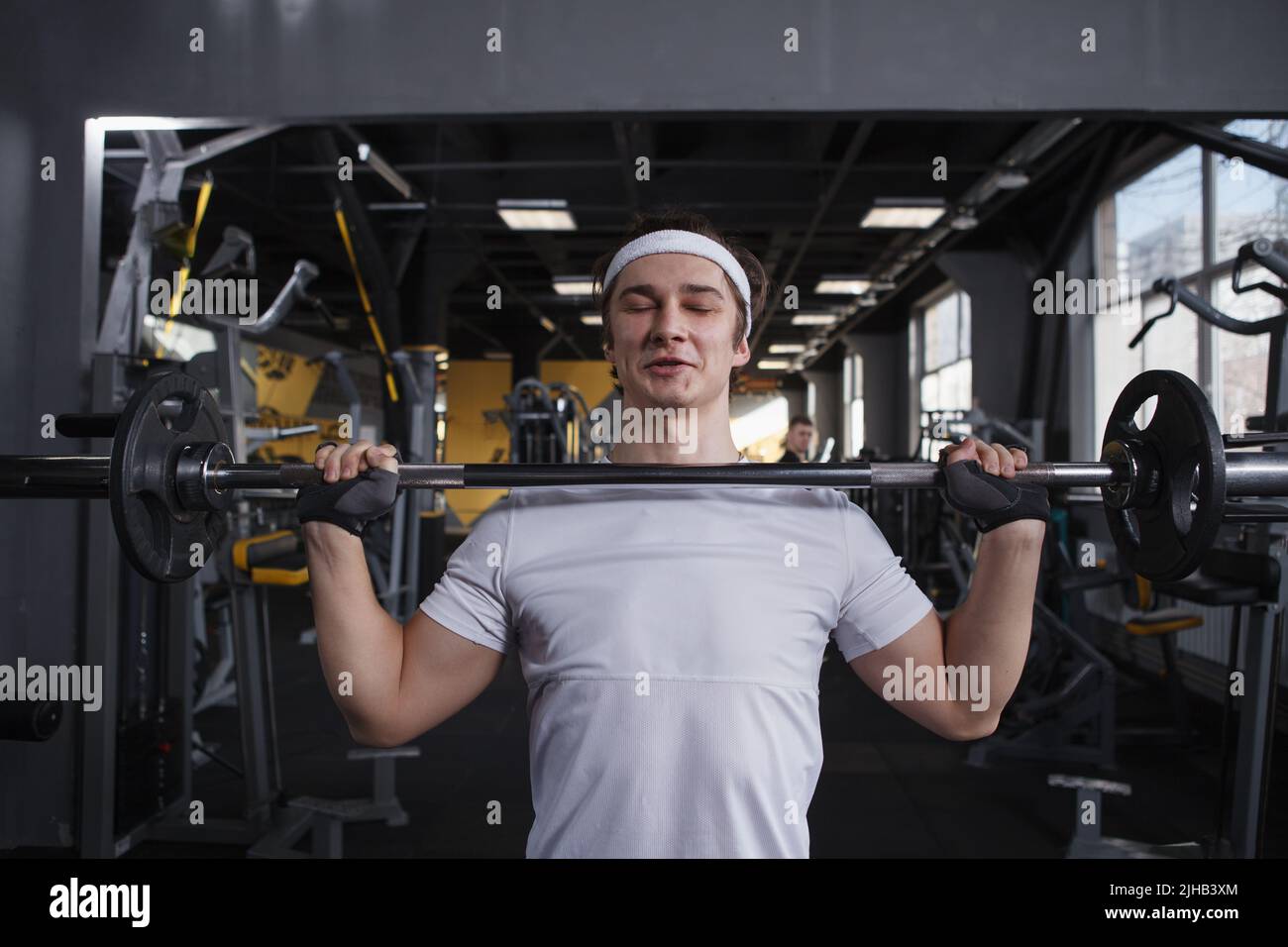 Strong healthy young man doing push press exercise with barbell Stock Photo