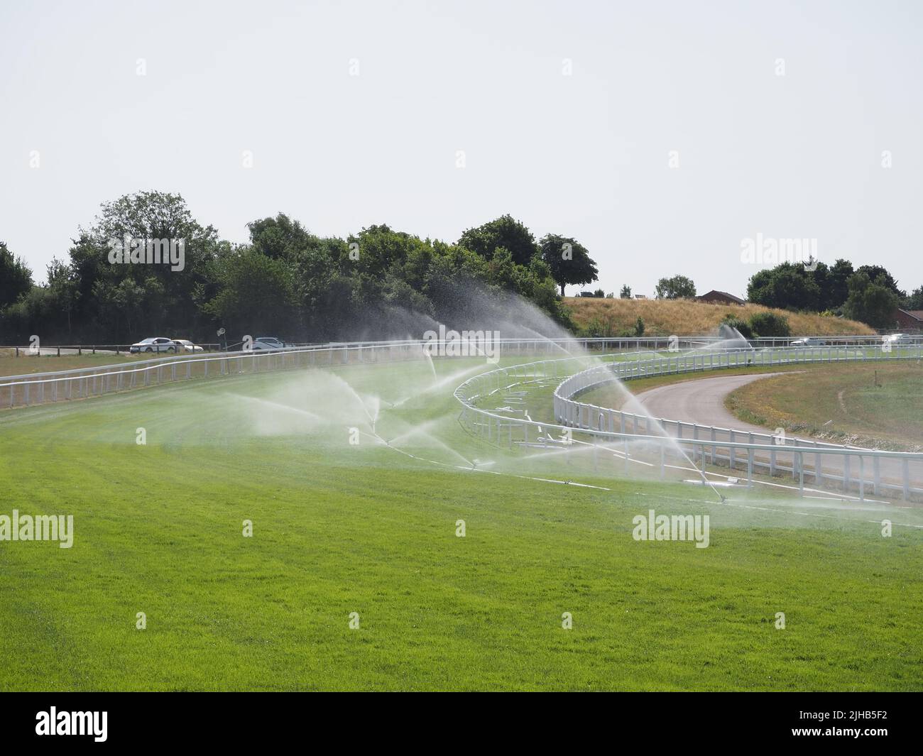 Epsom Downs, Surrey, England, UK. 17th July, 2022. During the exceptionally hot weather, the water sprinklers are working hard to keep the race course in top condition at Epsom Downs in Surrey. In contrast with the adjoining downs the course is looking lush and green. Credit: Julia Gavin/Alamy Live News Stock Photo